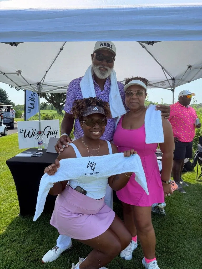 Three guests at the LivWizeGuy tent holding up and wearing LivWizeGuy towels