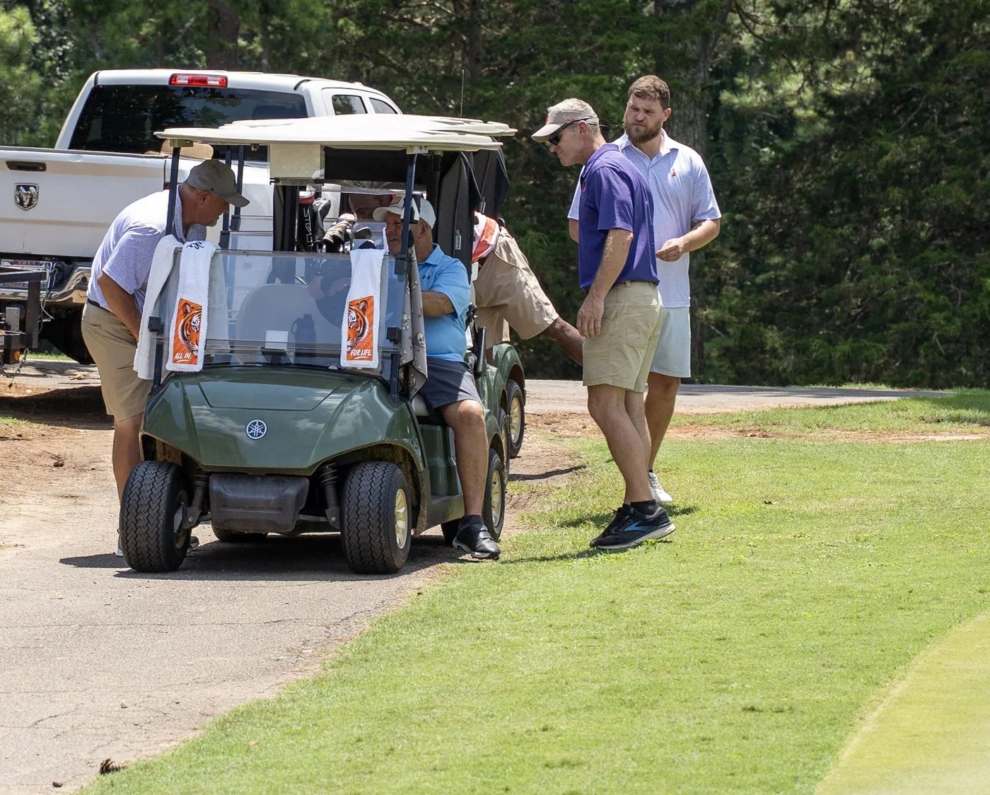 Golfers by a cart with Tiger towels hanging from the windshield