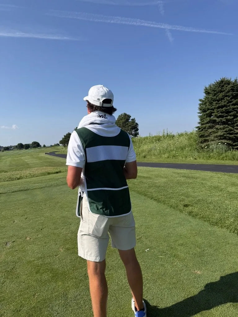 A caddie on the fairway with a LivWizeGuy towel around his neck