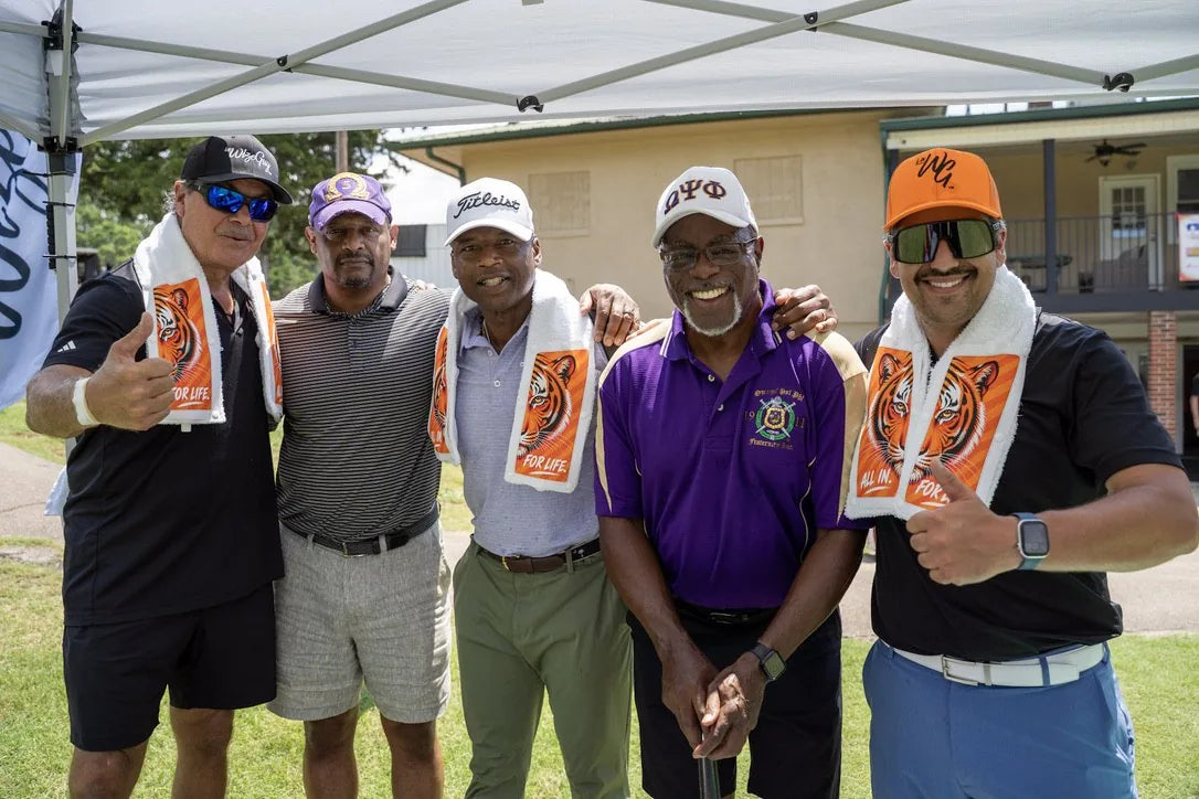 Five golfers under the LivWizeGuy tent, three wearing Tiger towels